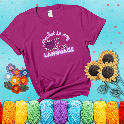 Say it with stitches Design reads 'Crochet Is My Love Language', perfect crochet gift for yarn lovers; showing a magenta tee with a teal sunflower background