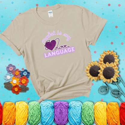Say it with stitches Design reads 'Crochet Is My Love Language', perfect crochet gift for yarn lovers; showing a beige tee with a teal sunflower background