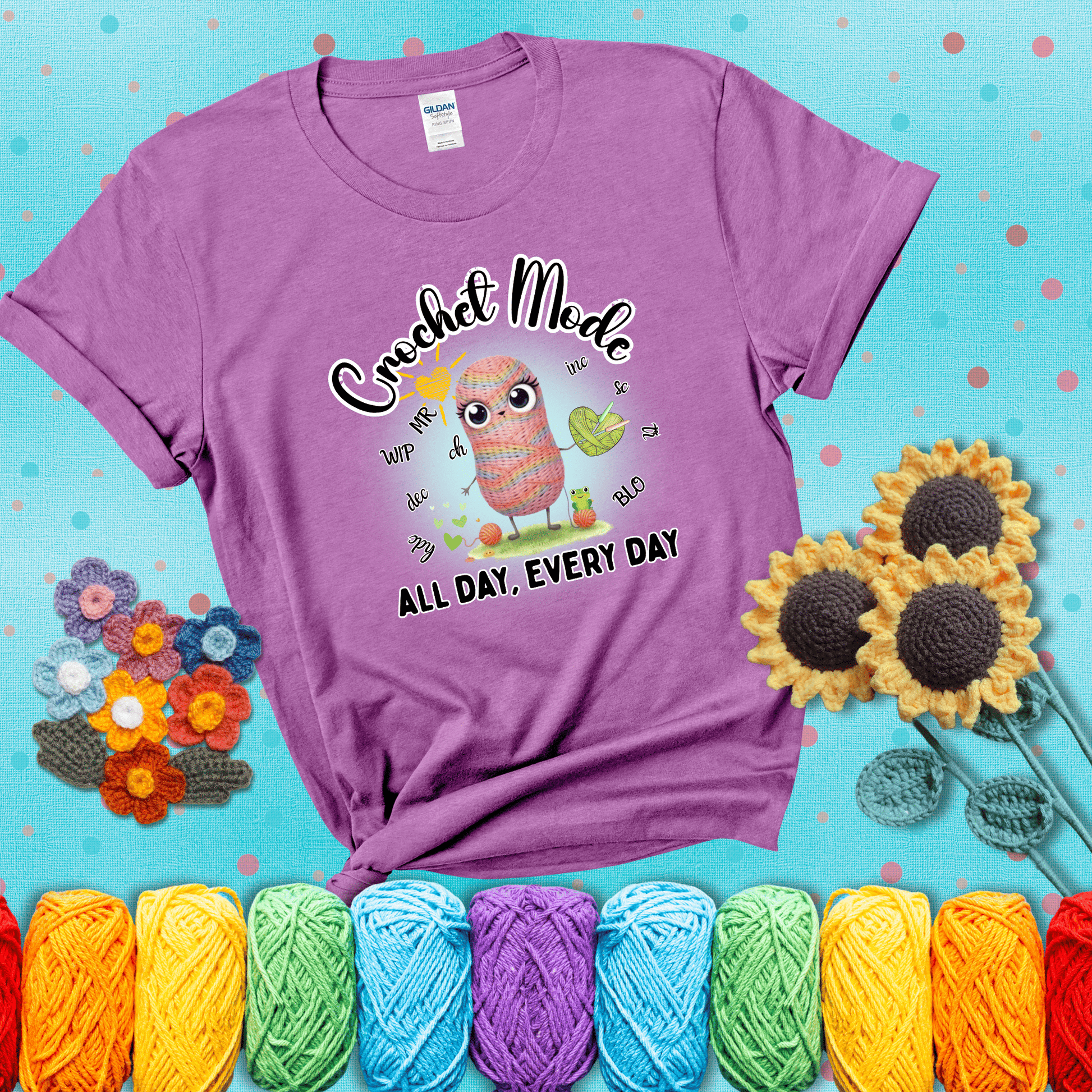 A kawaii-style rainbow yarn character surrounded by crochet stitch abbreviations and holding a yarn heart, with text “Crochet Mode All Day, Every Day"; showing a light purple tee with a teal sunflower background