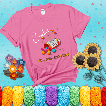 Orange prescription bottle spilling colorful yarn balls with text "Crochet – My Legal Addiction" and "Take as needed for maximum stress relief" showing a pink tee with a teal sunflower background
