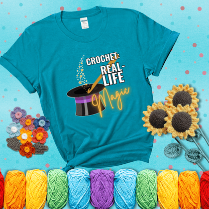 Poof! Stress gone Design reads 'Crochet: Real-Life Magic' , perfect crochet gift for yarn lovers; showing a blue-green tee with a teal sunflower background