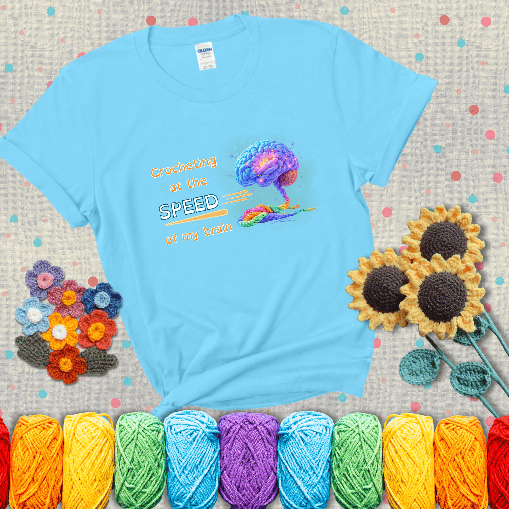 A glowing rainbow brain unravels into colorful yarn with the phrase “Crocheting at the speed of my brain;" showing a light blue tee with grey sunflower background