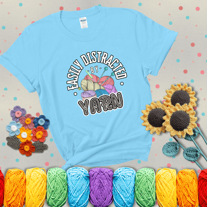 If yarn steals your focus every Design reads 'Easily Distracted By Yarn', perfect crochet gift for yarn lovers; showing a light blue tee with grey sunflower background