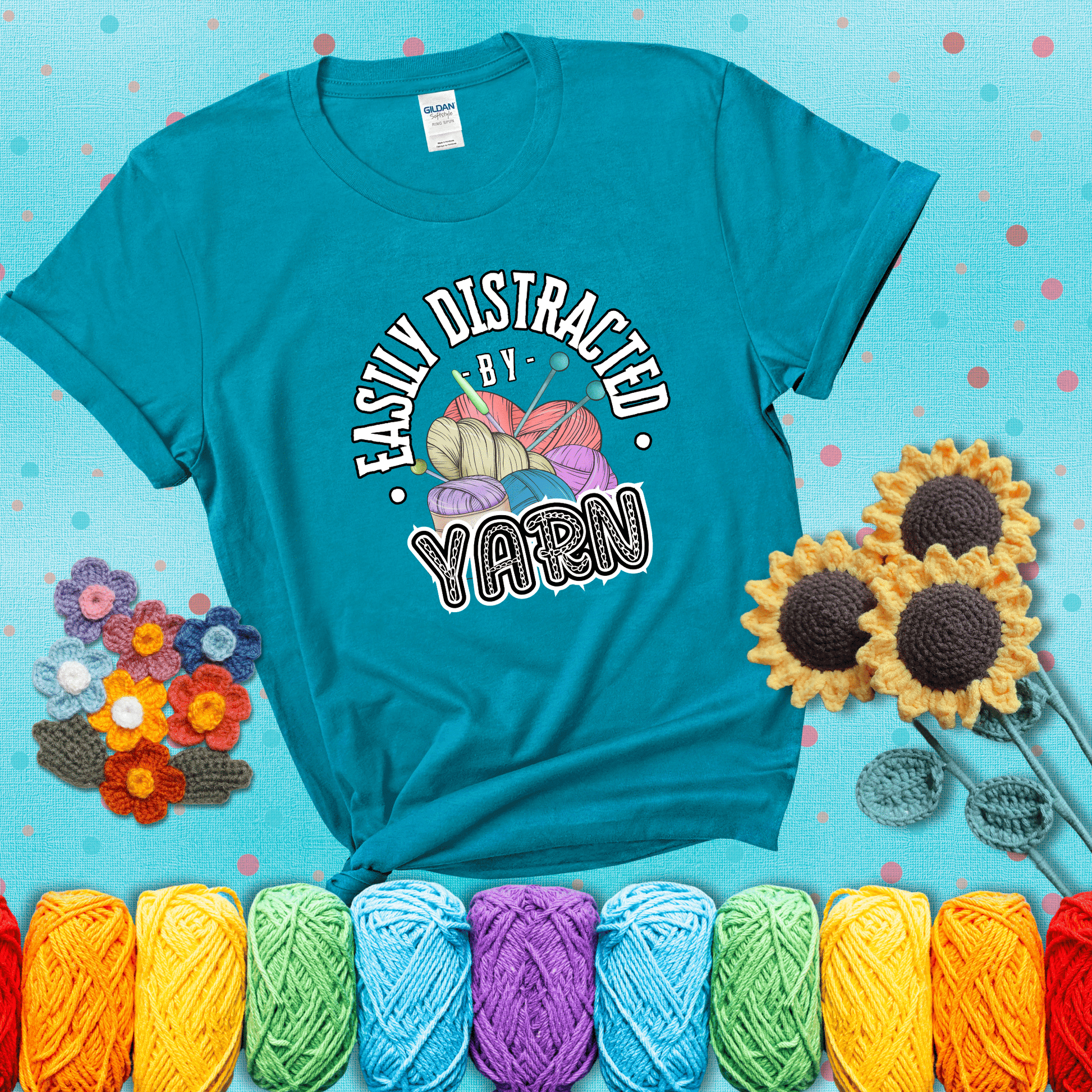 If yarn steals your focus every Design reads 'Easily Distracted By Yarn', perfect crochet gift for yarn lovers; showing a blue-green tee with a teal sunflower background