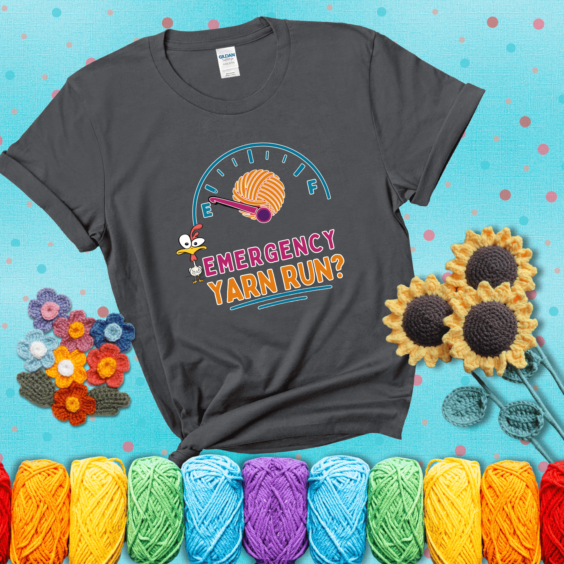 A fuel gauge with a ball of yarn as the needle pointing to empty, a frantic chicken, and the text “Emergency Yarn Run?” showing a dark grey tee with a teal sunflower background