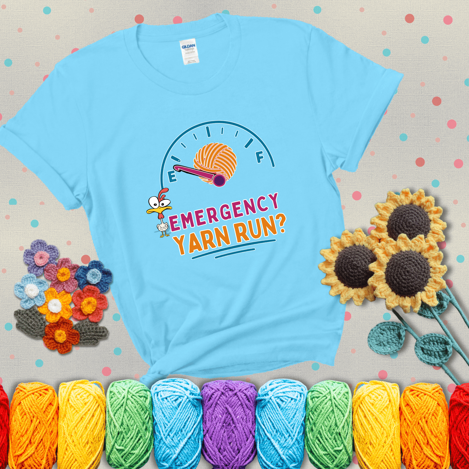 A fuel gauge with a ball of yarn as the needle pointing to empty, a frantic chicken, and the text “Emergency Yarn Run?” showing a light blue tee with grey sunflower background