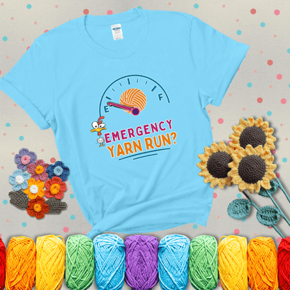 A fuel gauge with a ball of yarn as the needle pointing to empty, a frantic chicken, and the text “Emergency Yarn Run?” showing a light blue tee with grey sunflower background