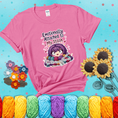 Rows of colorful yarn skeins stacked with playful text. Text reads: “Emotionally Attached to My Stash.” A humorous shirt for fiber lovers with growing collections, showing a pink tee with a teal sunflower background