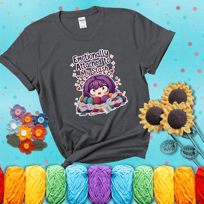 Rows of colorful yarn skeins stacked with playful text. Text reads: “Emotionally Attached to My Stash.” A humorous shirt for fiber lovers with growing collections, showing a dark grey tee with a teal sunflower background