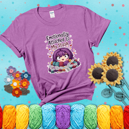 Rows of colorful yarn skeins stacked with playful text. Text reads: “Emotionally Attached to My Stash.” A humorous shirt for fiber lovers with growing collections, showing a light purple tee with a teal sunflower background