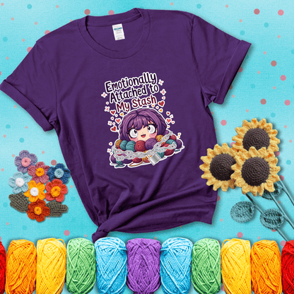 Rows of colorful yarn skeins stacked with playful text. Text reads: “Emotionally Attached to My Stash.” A humorous shirt for fiber lovers with growing collections, showing a purple tee with a teal sunflower background