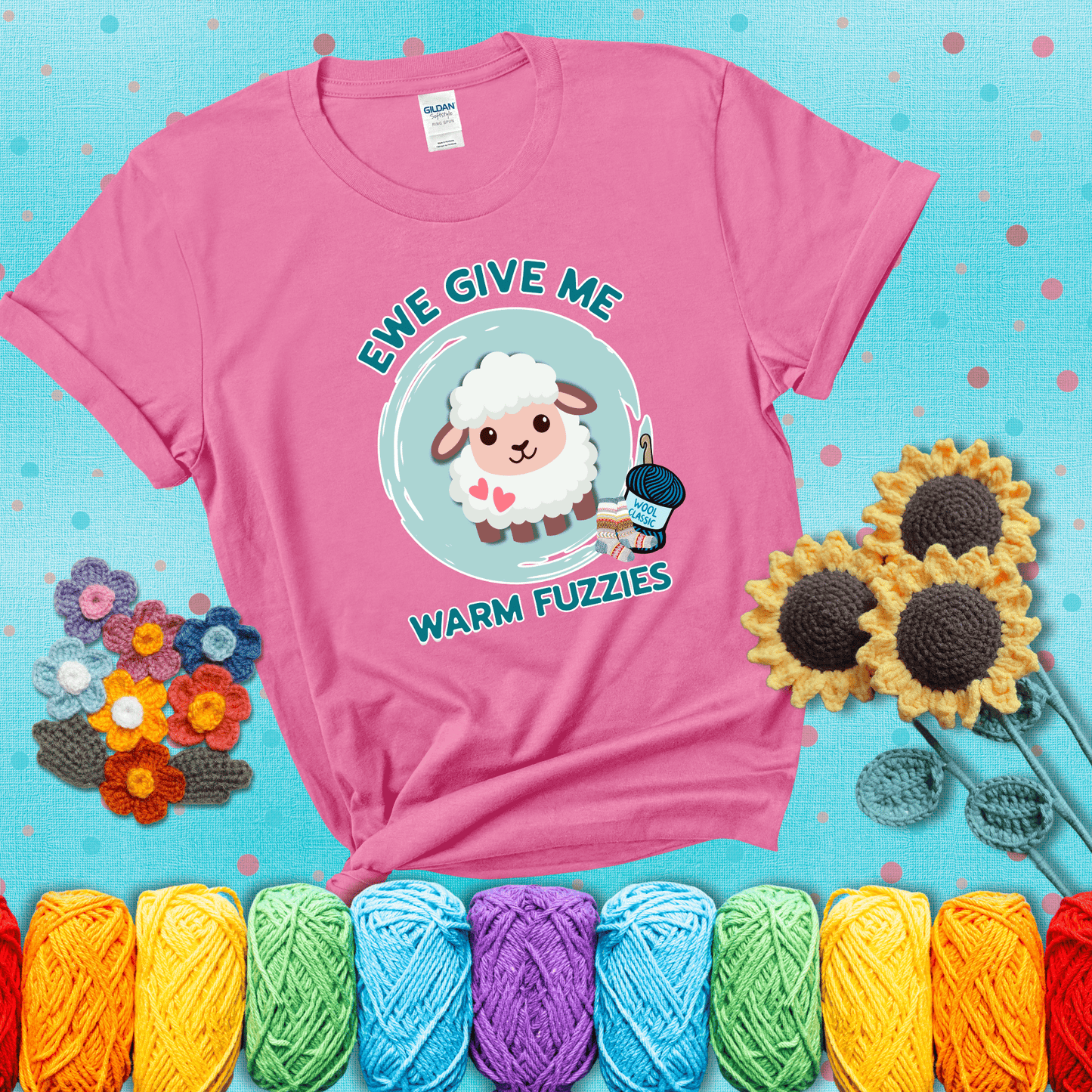 Cartoon sheep with pink hearts, wool socks, and yarn labeled “Wool Classic.” Text reads “Ewe Give Me Warm Fuzzies” showing a pink tee with a teal sunflower background
