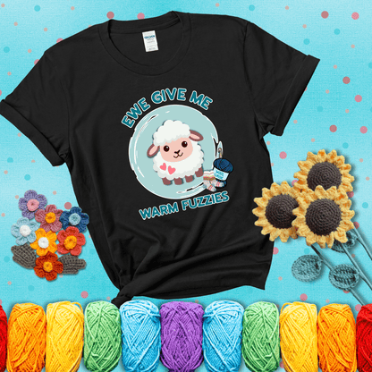 Cartoon sheep with pink hearts, wool socks, and yarn labeled “Wool Classic.” Text reads “Ewe Give Me Warm Fuzzies” showing a black tee with a teal sunflower background