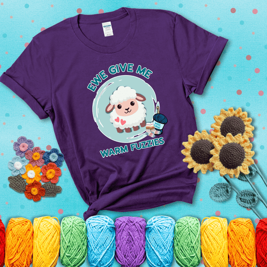Cartoon sheep with pink hearts, wool socks, and yarn labeled “Wool Classic.” Text reads “Ewe Give Me Warm Fuzzies” showing a purple tee with a teal sunflower background