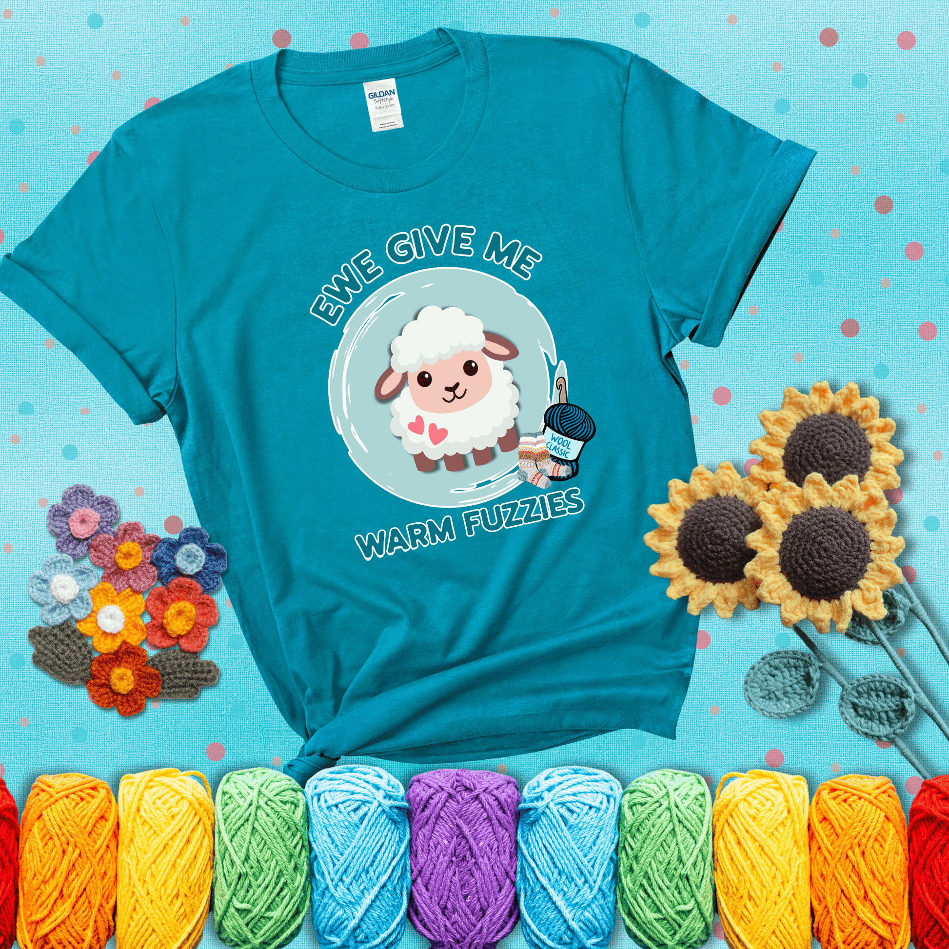 Cartoon sheep with pink hearts, wool socks, and yarn labeled “Wool Classic.” Text reads “Ewe Give Me Warm Fuzzies” showing a blue-green tee with a teal sunflower background