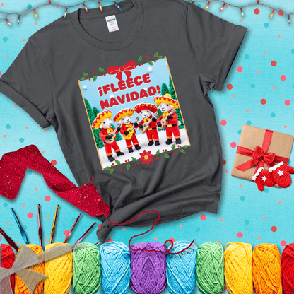 Four crocheted sheep dressed in red mariachi outfits with guitars, standing in a snowy scene under the phrase “¡Fleece Navidad!” showing a dark grey tee with a festive Christmas background