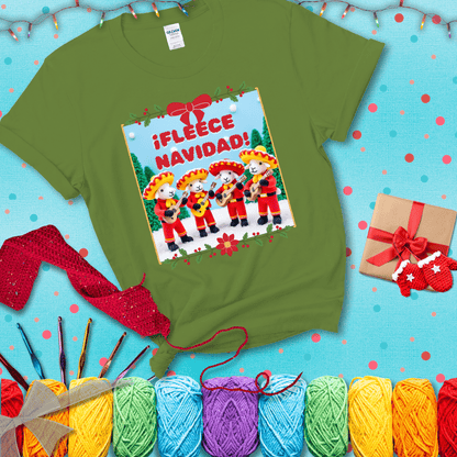 Four crocheted sheep dressed in red mariachi outfits with guitars, standing in a snowy scene under the phrase “¡Fleece Navidad!” showing a bright green tee with a festive Christmas background