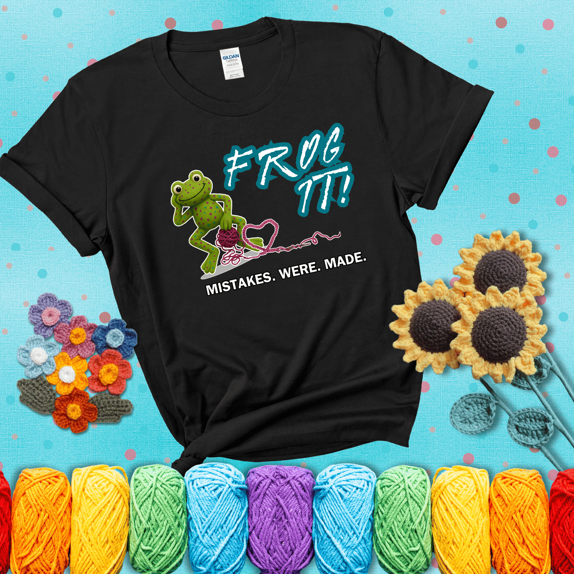 Green frog with yarn and heart-shaped loop. Text reads: “Frog It! Mistakes Were Made.” A playful crochet tee for anyone who's ever had to rip it back, showing a black tee with a teal sunflower background