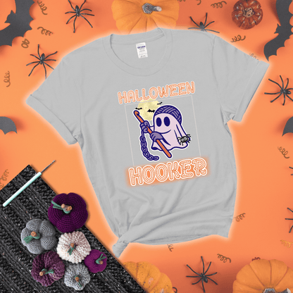 Cartoon ghost crocheter with a yarn ball head, crochet hook, bats, and text “Halloween Hooker,” a fun spooky tee for yarn lovers showing a light grey tee with a festive Halloween background