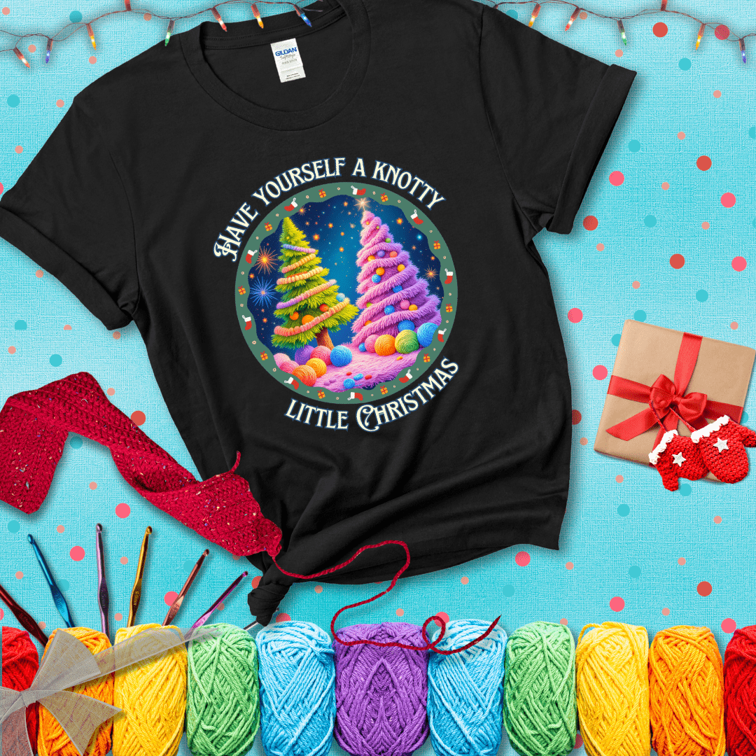 Two yarn-covered Christmas trees wrapped in colorful strands of yarn, with the phrase "Have Yourself a Knotty Little Christmas" encircling the scene showing a black tee with a festive Christmas background