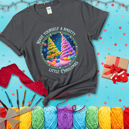 Two yarn-covered Christmas trees wrapped in colorful strands of yarn, with the phrase "Have Yourself a Knotty Little Christmas" encircling the scene showing a dark grey tee with a festive Christmas background