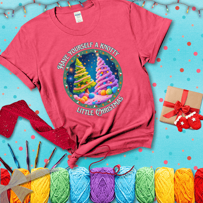 Two yarn-covered Christmas trees wrapped in colorful strands of yarn, with the phrase "Have Yourself a Knotty Little Christmas" encircling the scene showing a light red tee with a festive Christmas background