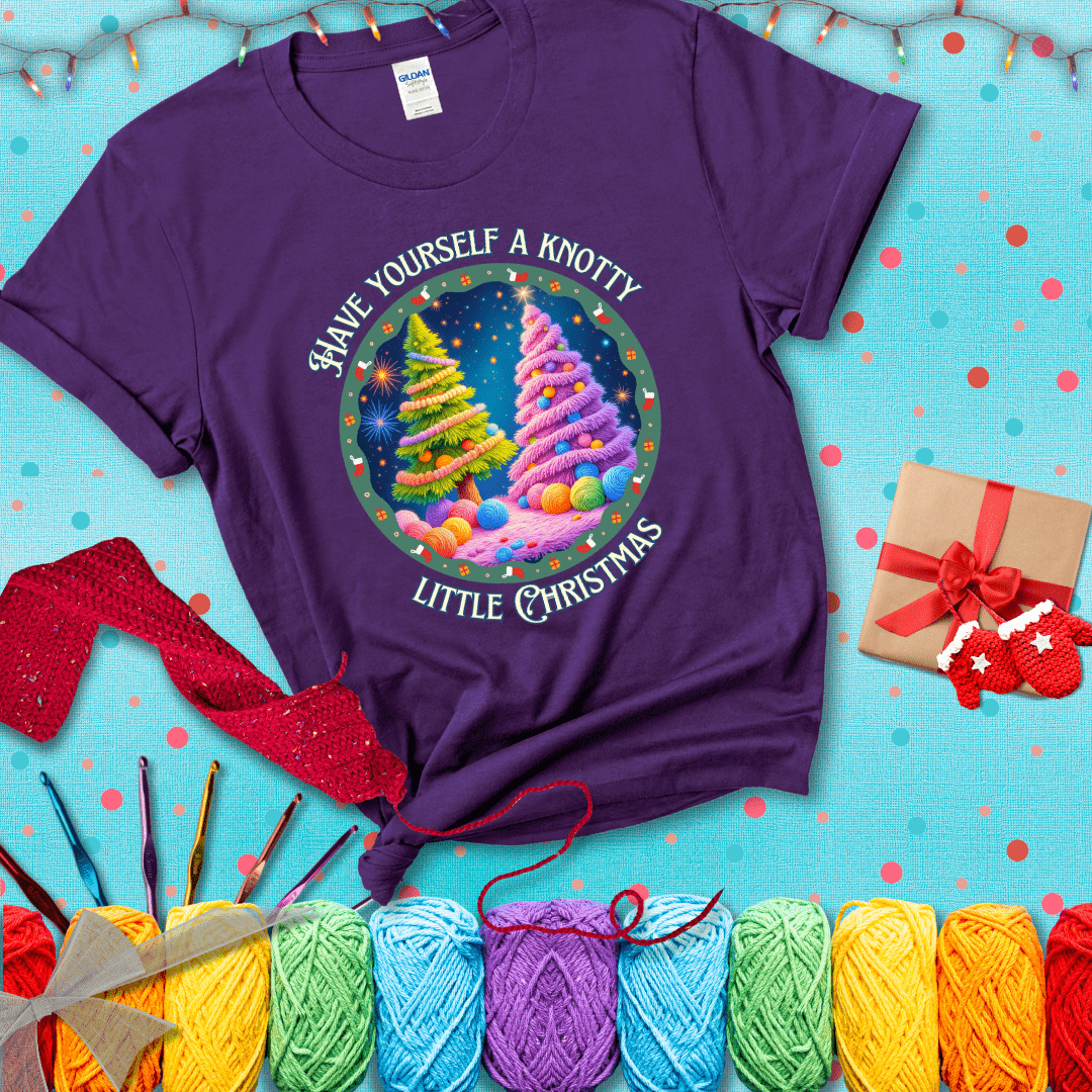 Two yarn-covered Christmas trees wrapped in colorful strands of yarn, with the phrase "Have Yourself a Knotty Little Christmas" encircling the scene showing a purple tee with a festive Christmas background