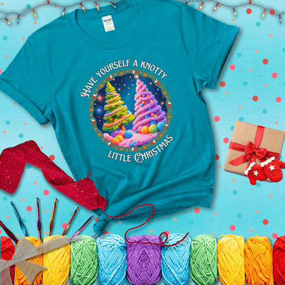 Two yarn-covered Christmas trees wrapped in colorful strands of yarn, with the phrase "Have Yourself a Knotty Little Christmas" encircling the scene showing a blue-green tee with a festive Christmas background