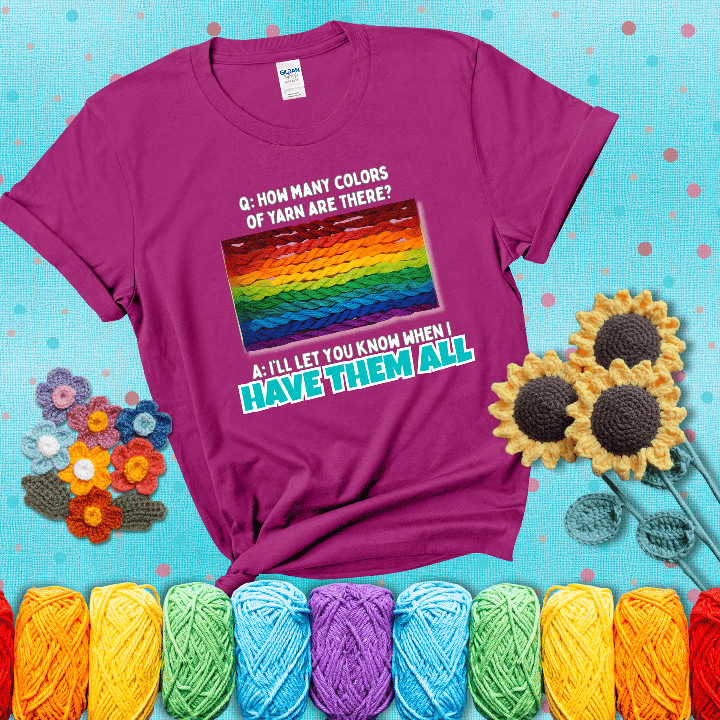 Rainbow skeins of yarn stacked in color gradient with playful question: “How many colors of yarn are there?” Answer: “I'll let you know when I have them all” showing a magenta tee with a teal sunflower background
