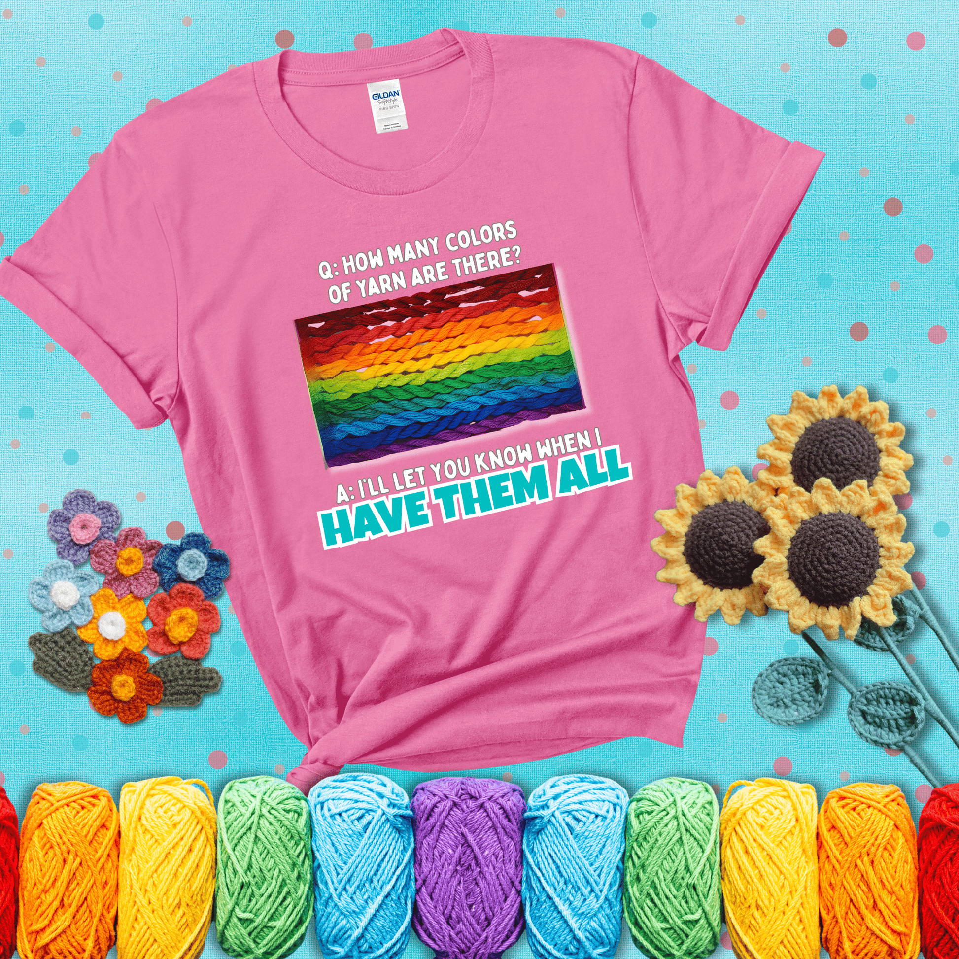 Rainbow skeins of yarn stacked in color gradient with playful question: “How many colors of yarn are there?” Answer: “I'll let you know when I have them all” showing a pink tee with a teal sunflower background