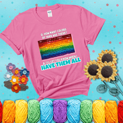 Rainbow skeins of yarn stacked in color gradient with playful question: “How many colors of yarn are there?” Answer: “I'll let you know when I have them all” showing a pink tee with a teal sunflower background
