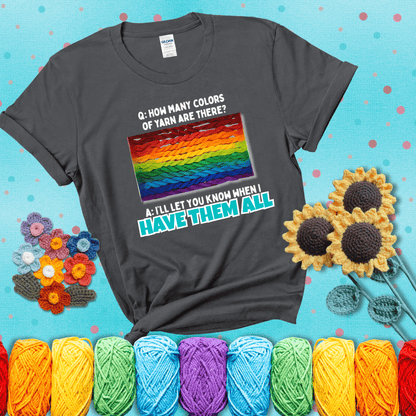 Rainbow skeins of yarn stacked in color gradient with playful question: “How many colors of yarn are there?” Answer: “I'll let you know when I have them all” showing a dark grey tee with a teal sunflower background