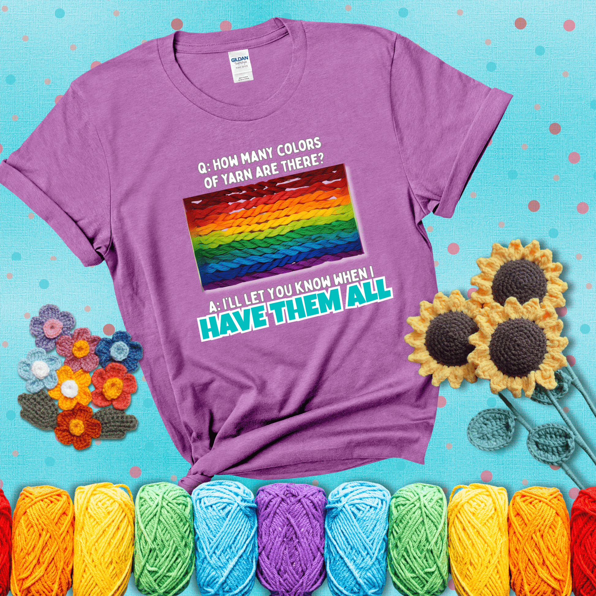 Rainbow skeins of yarn stacked in color gradient with playful question: “How many colors of yarn are there?” Answer: “I'll let you know when I have them all” showing a light purple tee with a teal sunflower background