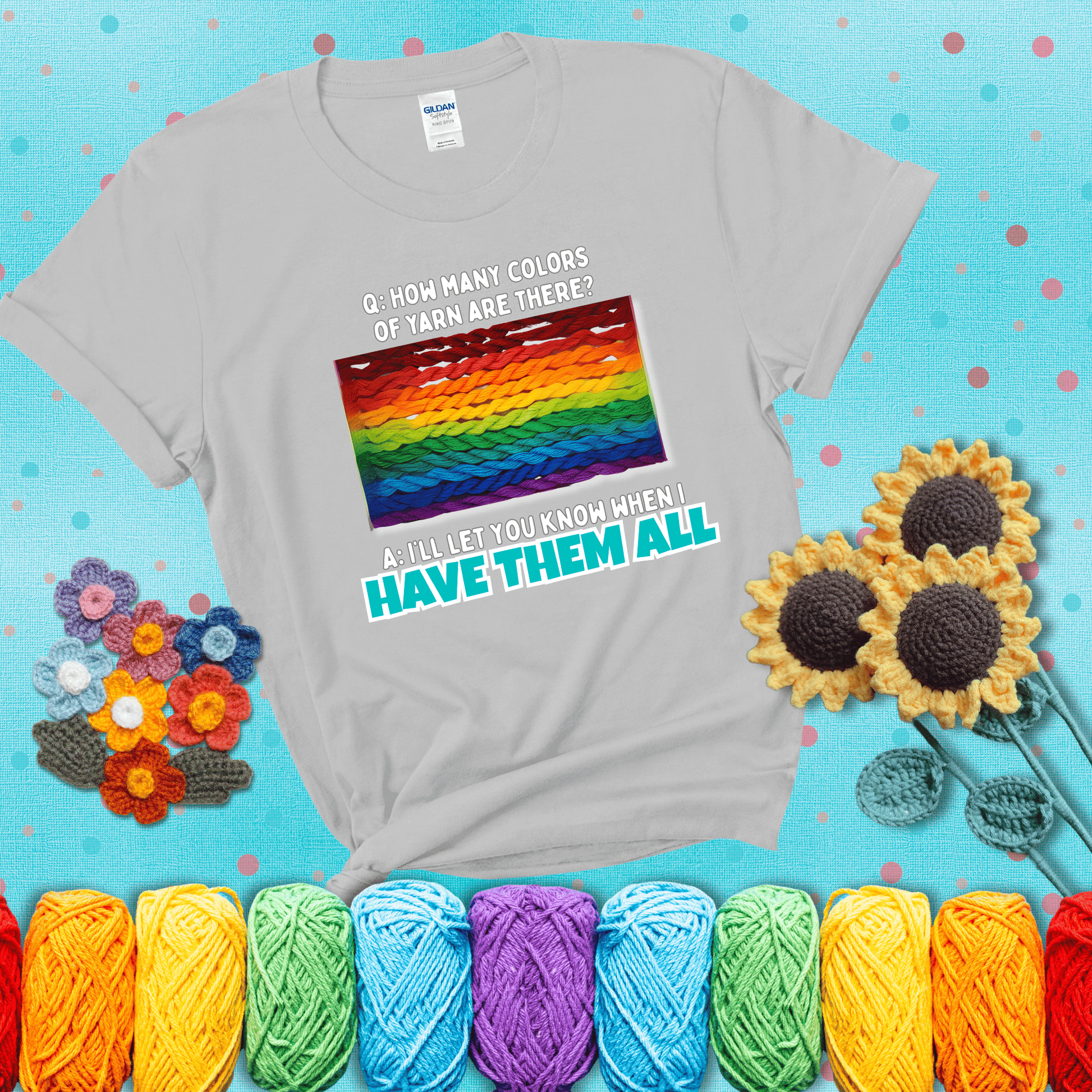Rainbow skeins of yarn stacked in color gradient with playful question: “How many colors of yarn are there?” Answer: “I'll let you know when I have them all” showing a light grey tee with a teal sunflower background