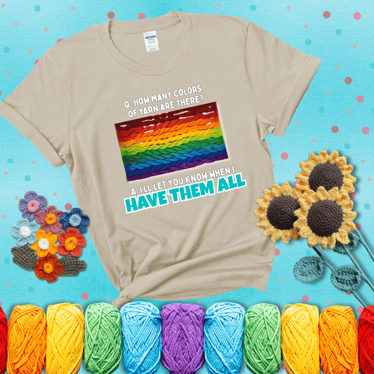 Rainbow skeins of yarn stacked in color gradient with playful question: “How many colors of yarn are there?” Answer: “I'll let you know when I have them all” showing a beige tee with a teal sunflower background
