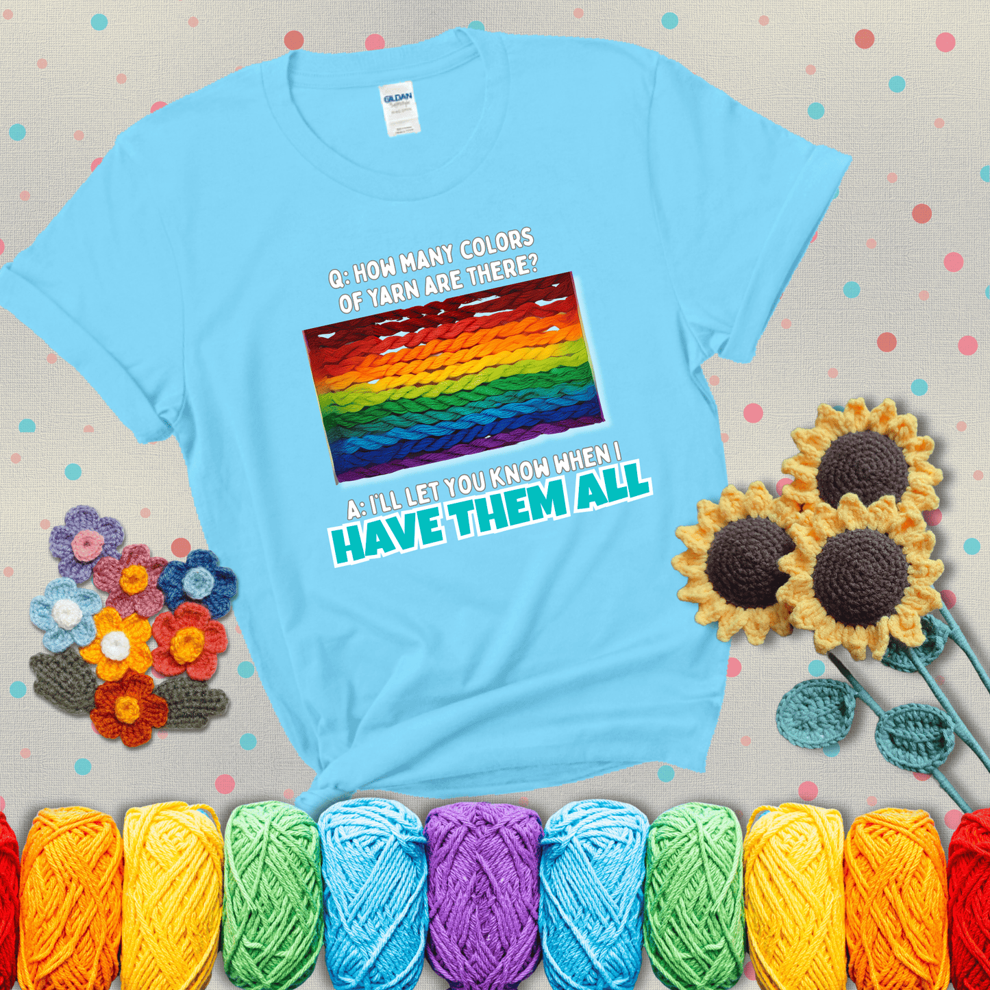 Rainbow skeins of yarn stacked in color gradient with playful question: “How many colors of yarn are there?” Answer: “I'll let you know when I have them all” showing a light blue tee with grey sunflower background