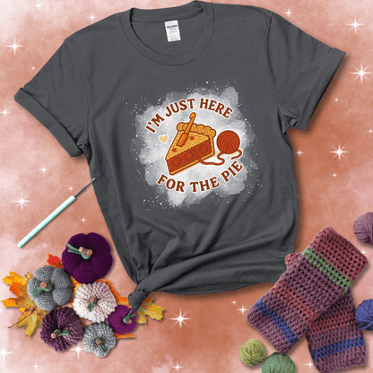 A slice of cherry pie with a crochet hook tucked in the filling and yarn trailing out, blending baking with crochet fun, showing a dark grey tee with a festive Fall background