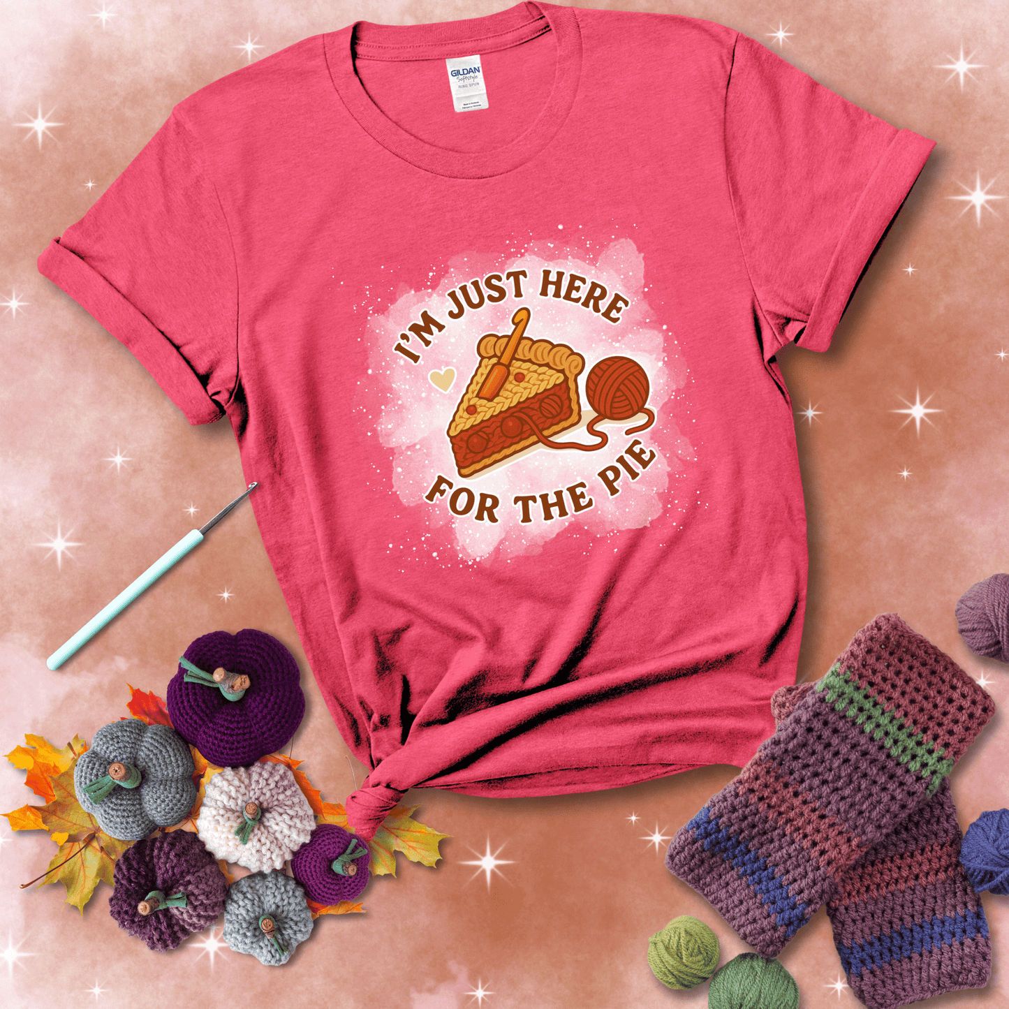 A slice of cherry pie with a crochet hook tucked in the filling and yarn trailing out, blending baking with crochet fun, showing a light red tee with a festive Fall background