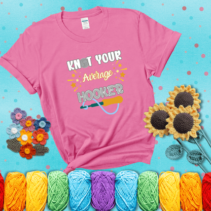 Bold lettering with a yarn hook graphic. Text reads: “I'm Not Your Average Hooker.” A cheeky crochet tee for confident crafters who own their skills, showing a pink tee with a teal sunflower background