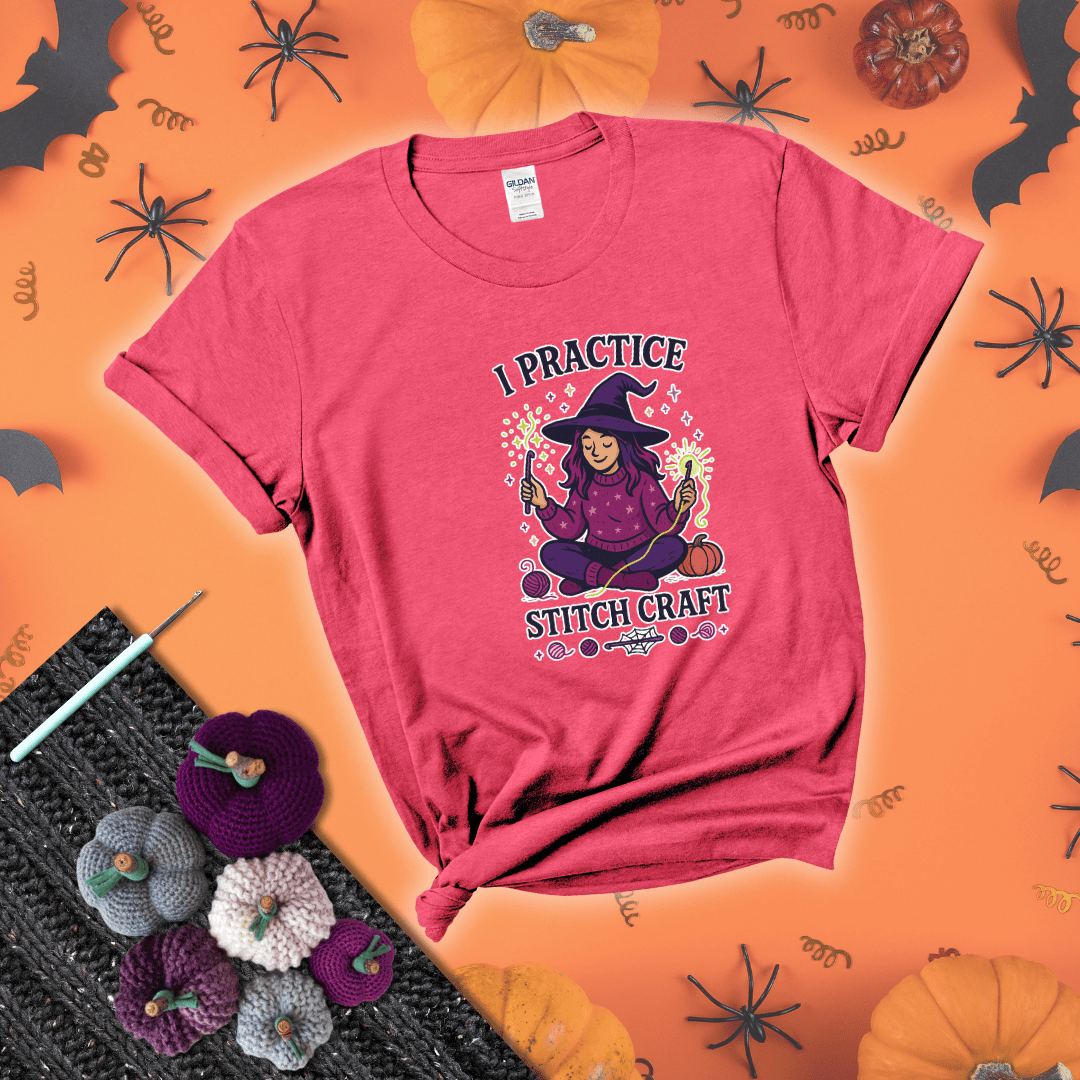 Witchy crocheter sits cross-legged, conjuring yarn magic with crochet hooks and glowing green yarn, surrounded by stars, pumpkins, and stitchy vibes showing a light red tee with a festive Halloween background