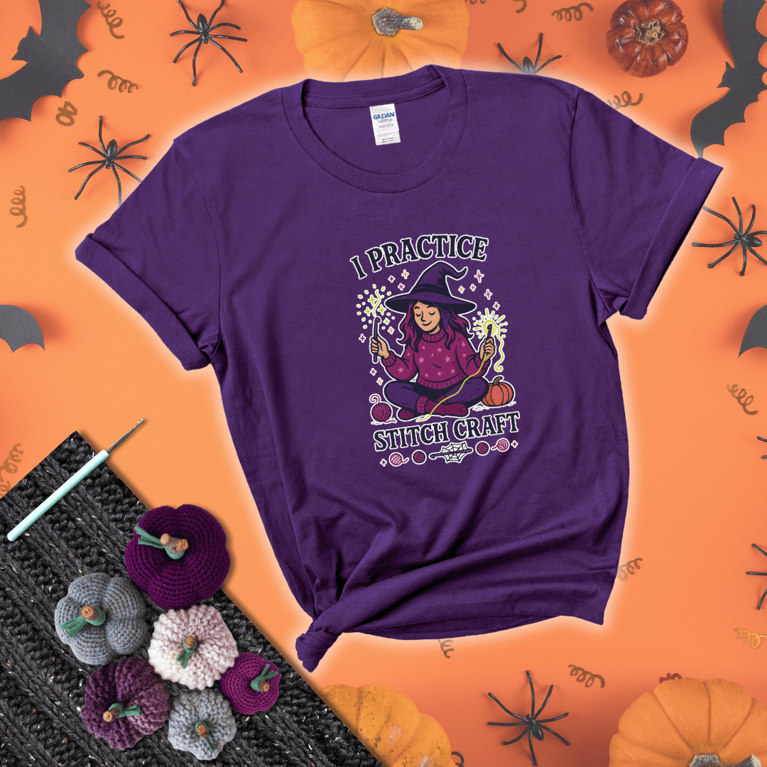 Witchy crocheter sits cross-legged, conjuring yarn magic with crochet hooks and glowing green yarn, surrounded by stars, pumpkins, and stitchy vibes showing a purple tee with a festive Halloween background