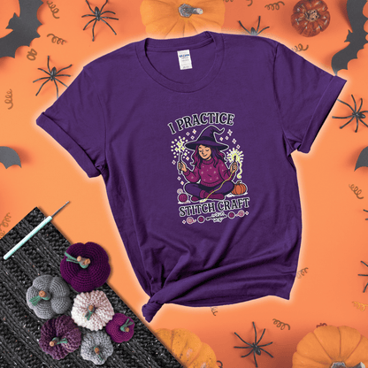 Witchy crocheter sits cross-legged, conjuring yarn magic with crochet hooks and glowing green yarn, surrounded by stars, pumpkins, and stitchy vibes showing a purple tee with a festive Halloween background
