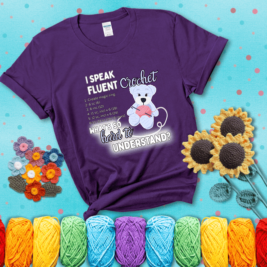 A cute crochet bear holding a yarn ball, surrounded by a short crochet pattern. The phrase reads “I Speak Fluent Crochet – What’s so hard to understand?” showing a purple tee with a teal sunflower background