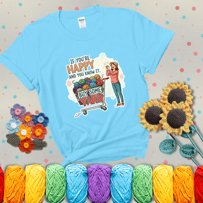 Woman clapping beside a shopping cart overflowing with colorful yarn balls, styled with cheerful pastel accents and bold playful lettering showing a light blue tee with grey sunflower background