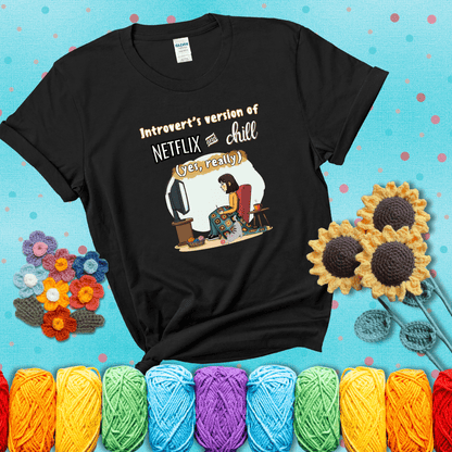 A girl with a crochet hook sits under a granny square blanket watching TV, with yarn, a coffee mug, and a cat at her feet. Text says “Introvert’s version of Netflix and chill (yes, really)," showing a black tee with a teal sunflower background