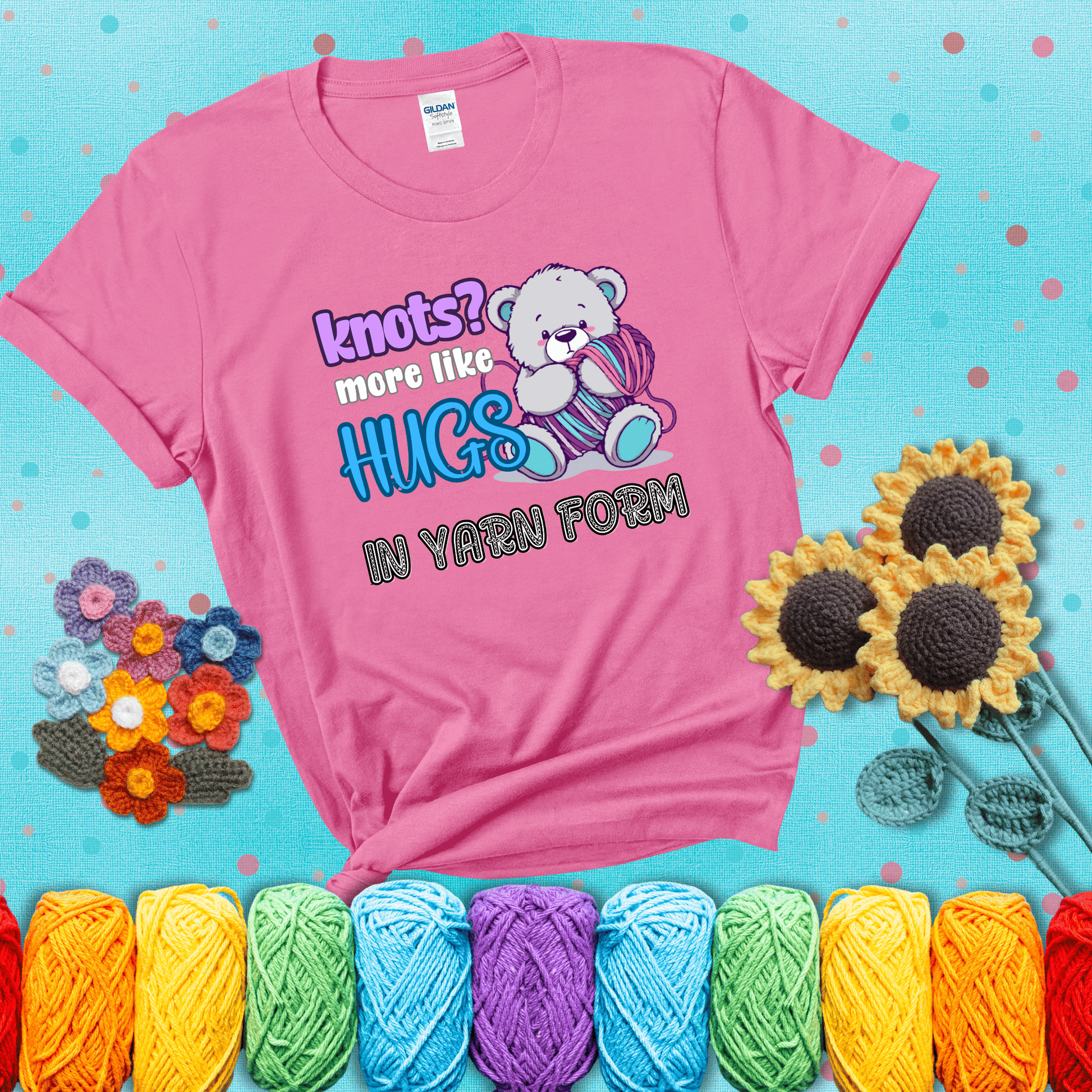 Cute teddy bear holding colorful yarn ball with hearts. Text reads: “Knots? More Like Hugs in Yarn Form.” Perfect for cozy gift-givers and yarn lovers, showing a pink tee with a teal sunflower background