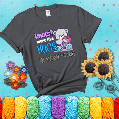 Cute teddy bear holding colorful yarn ball with hearts. Text reads: “Knots? More Like Hugs in Yarn Form.” Perfect for cozy gift-givers and yarn lovers, showing a dark grey tee with a teal sunflower background