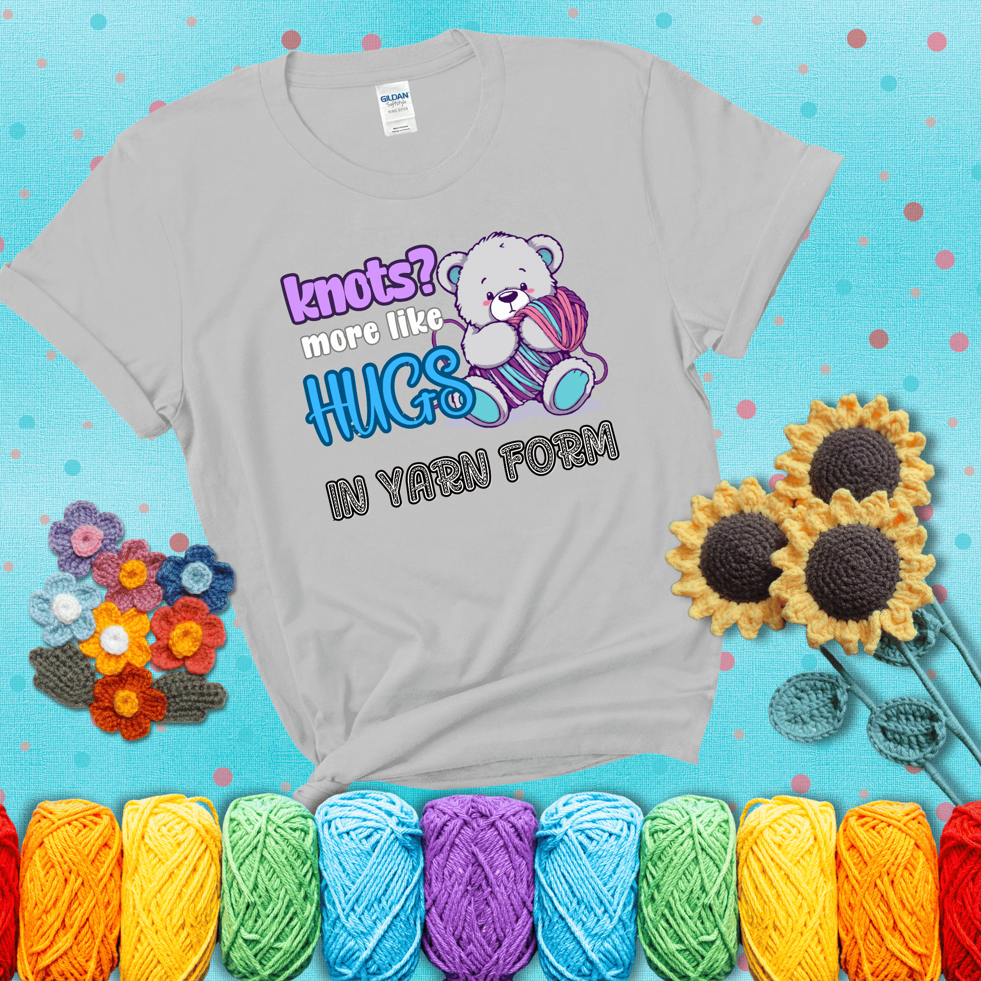 Cute teddy bear holding colorful yarn ball with hearts. Text reads: “Knots? More Like Hugs in Yarn Form.” Perfect for cozy gift-givers and yarn lovers, showing a light grey tee with a teal sunflower background