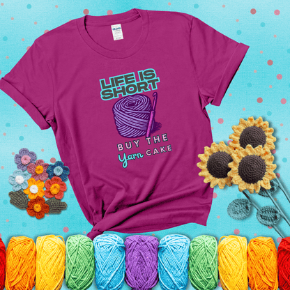 No regrets, just yarn Design reads 'Life Is Short. Buy The Yarn (Cake)' , perfect crochet gift for yarn lovers, showing a magenta tee with a teal sunflower background