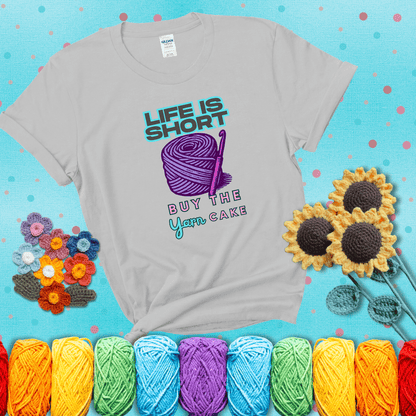 No regrets, just yarn Design reads 'Life Is Short. Buy The Yarn (Cake)' , perfect crochet gift for yarn lovers, showing a light grey tee with a teal sunflower background